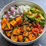 Close-up view of a Ground Beef Cottage Cheese Bowl featuring diced sweet potatoes and garnishes.