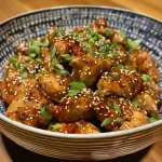 ['Juicy sesame chicken garnished with sesame seeds, served on a plate.', 'Close-up view of healthy sesame chicken dish showcasing tender chicken pieces.', 'Side view of sesame chicken with a shiny glaze and sesame seeds on top.', 'Healthy sesame chicken with vibrant colors, displayed attractively on a dish.']