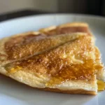 Close-up of fluffy keto pancakes stacked on a plate, glistening with syrup.