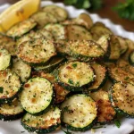 Close-up of crispy air-fried zucchini with a golden-brown crust on a white plate.