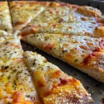 Close-up view of a golden-brown cottage cheese pizza crust on a wooden cutting board.