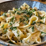 Close-up view of creamy Pfifferlinge pasta garnished with herbs.