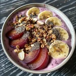 A vibrant plum smoothie bowl topped with fresh fruits and nuts.